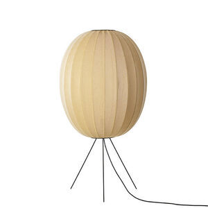 Oval gulvlampe med strikket overflade og moderne design på trefod.